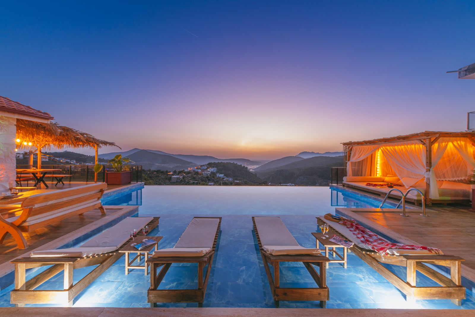 An infinity pool and sun loungers with a mountain view